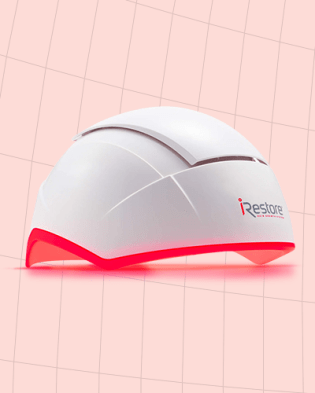 The iRestore Professional laser cap for hair growth against a pale red background.