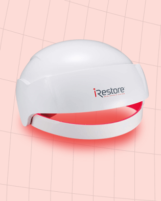 The iRestore Essential laser cap for hair growth against a pale red background.